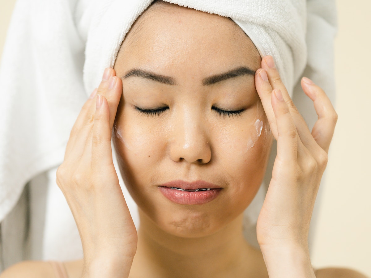 A girl applying a Snail Mucin product to her face, enjoying a rejuvenating skincare routine